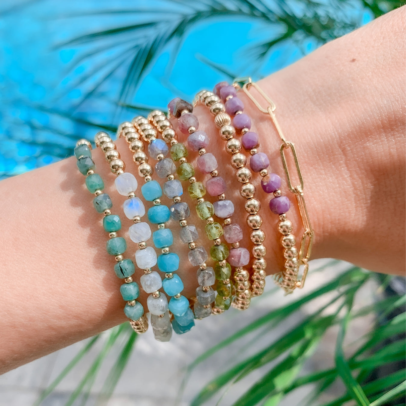 Gold Beaded Bracelet Stack Set on wrist with faceted gemstones closeup with tropical background - Blooming Lotus Jewelry