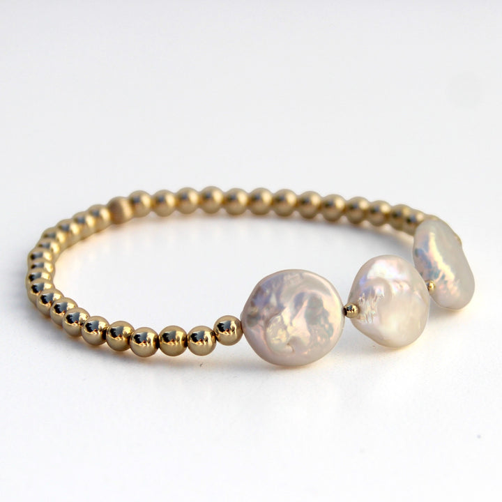 Side view of a gold beaded bracelet featuring three lustrous freshwater pearl coins, showcasing an elegant and natural design inspired by coastal beauty.