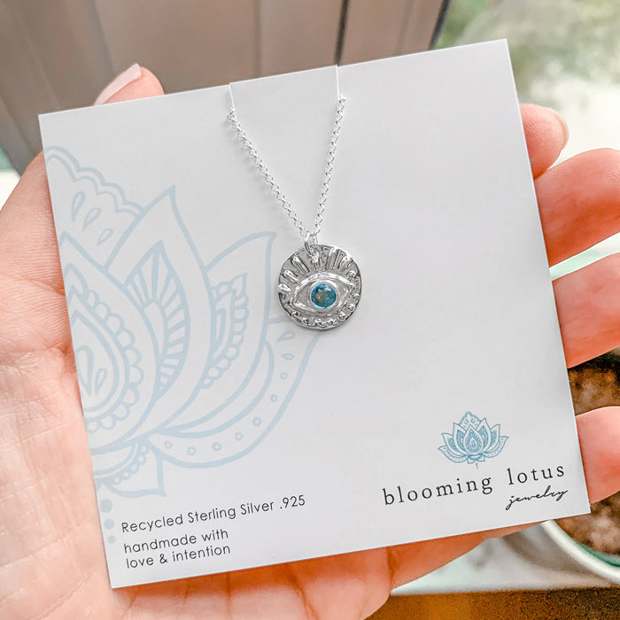 Evil Eye Necklace with Blue Topaz on square jewelry card held in hand