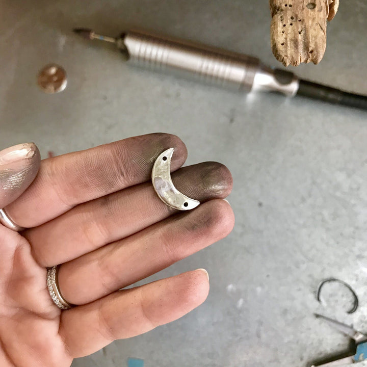 Luna crescent moon charm after polishing in jeweler's hand at jeweler's bench - Blooming Lotus Jewelry