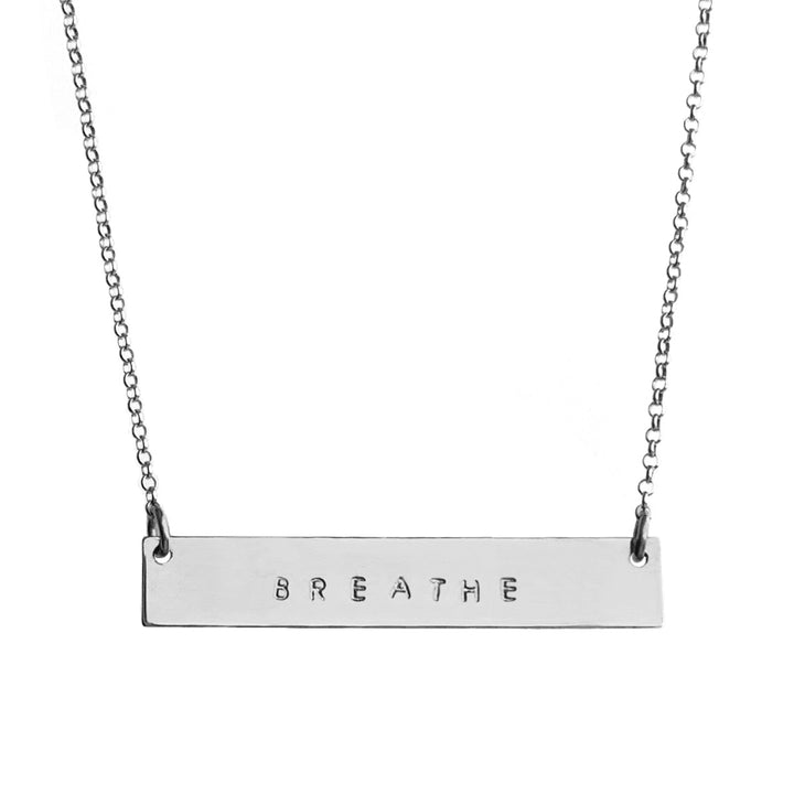 Silver Mantra Bar Necklace engraved with the word 'BREATHE,' hanging on a delicate silver chain, symbolizing mindfulness and simplicity. Handmade by Blooming Lotus Jewelry.