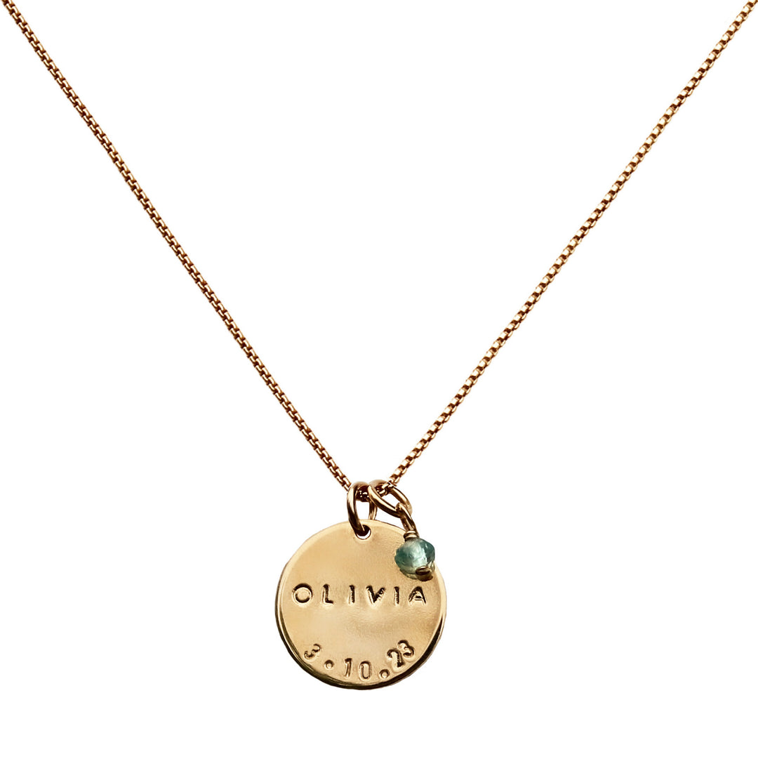 Gold Birthdate Necklace with hand-stamped name and date on a 16mm disc, accented with an aquamarine birthstone. Handmade by Blooming Lotus Jewelry.