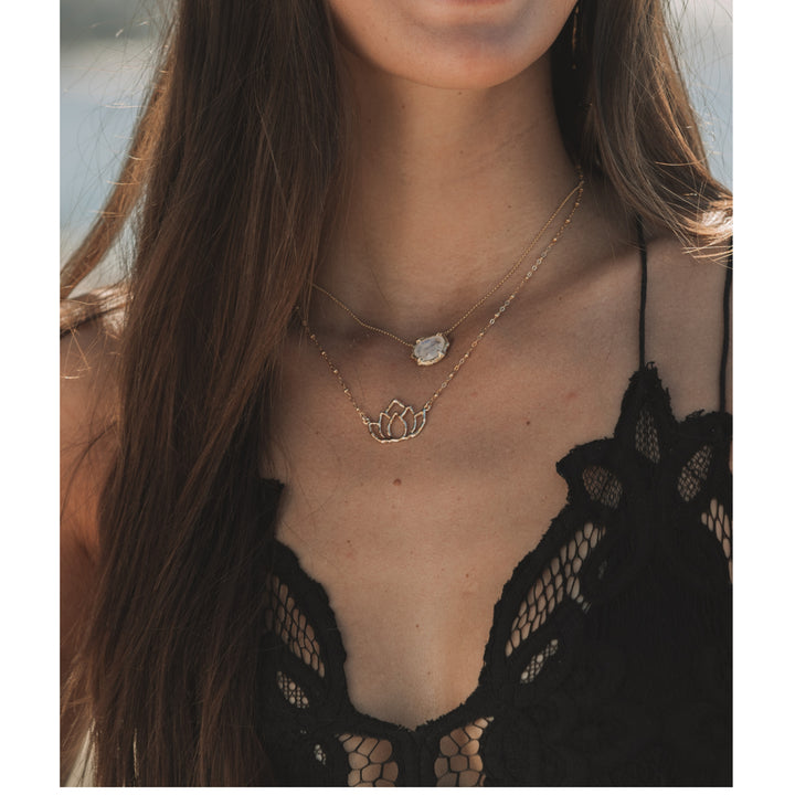 Blooming Lotus gold lotus pendant layered with a moonstone necklace, worn with a black lace top in natural light. A meaningful, yoga inspired jewelry look reflecting mindfulness and intention.