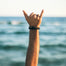 two mens wrist malas on wrist with man making shaka sign with ocean in background