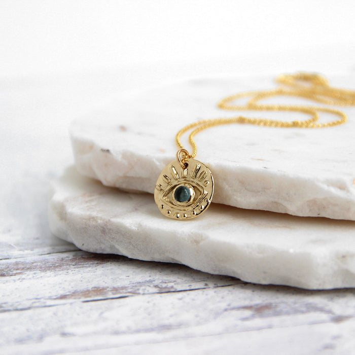 Evil Eye of Protection Necklace - gold with blue Topaz - on marble slab - Blooming Lotus Jewelry