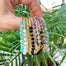 Gold Beaded Bracelets with faceted gemstones held in hand with plants in background - Blooming Lotus Jewelry