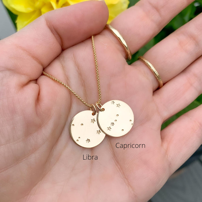 Libra and Capricorn Constellation Pendants on gold chain necklace in hand - Blooming Lotus Jewelry