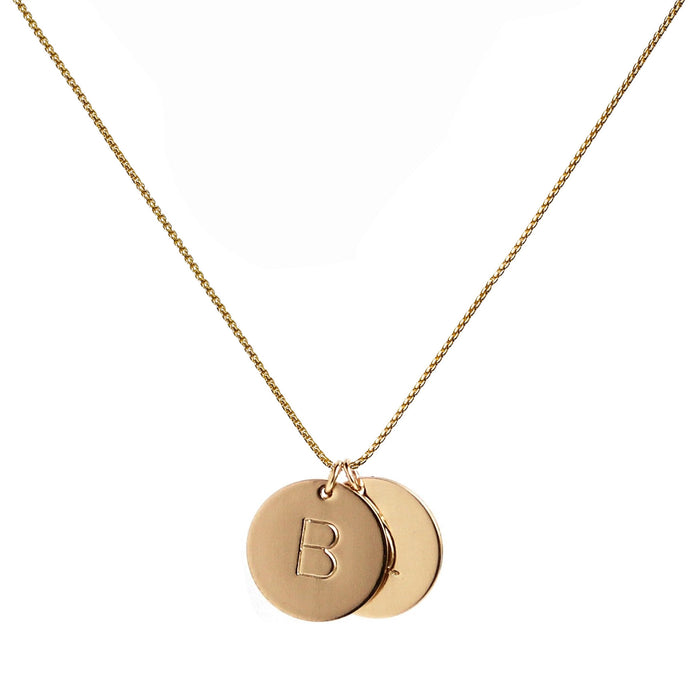 two gold initial disc coin pendants hanging from gold chain hand-stamped with capital B and Q
