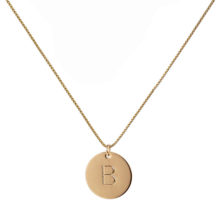single gold initial disc coin pendant hanging from gold chain hand-stamped with capital B