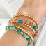gold beaded stacking bracelets with shells and turquoise cubed beads on wrist close up