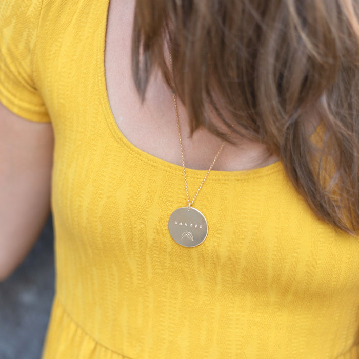 Gold Mantra Coin Necklace personalized with Wander 26 inches on model with yellow dress