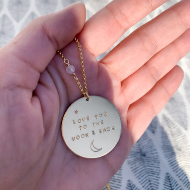 Gold Love You to the Moon and Back necklace on gold chain with tiny moonstone hand-stamped in hand