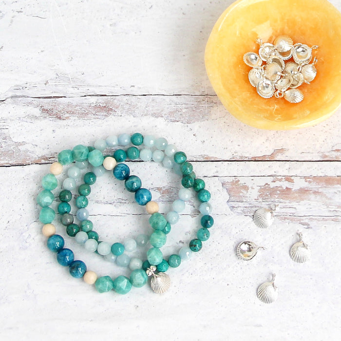 Ocean inspired gemstone bracelets with silver shell charm and yellow trinket dish filled with shell charms - Blooming Lotus Jewelry