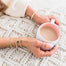 Gold beaded layering braclets on model holding coffee mug - Blooming Lotus Jewelry