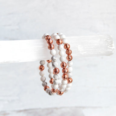 Howlite gemstone bracelets with rose gold lava beads hanging on selenite gemstone wand - Blooming Lotus Jewelry