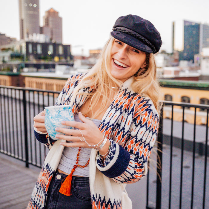 boho mala beads on model with bohemian sweater holding coffee mug on roof deck 