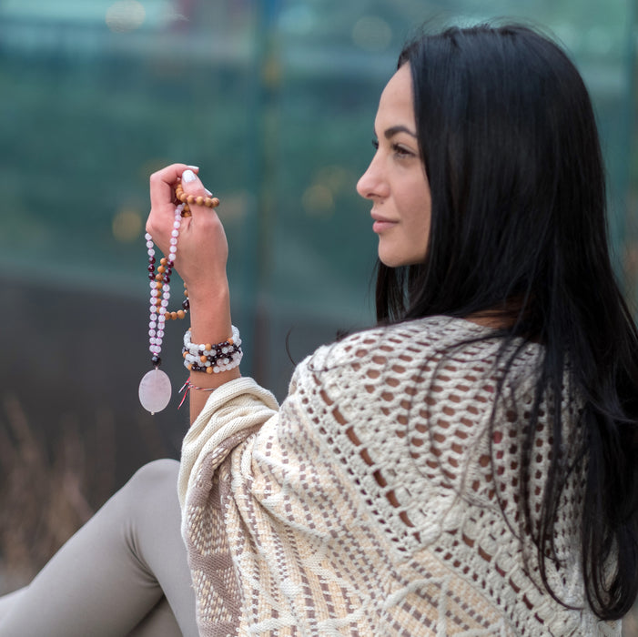 boho mala beads necklace held in hand with large rose quartz focal stone - blooming lotus jewelry